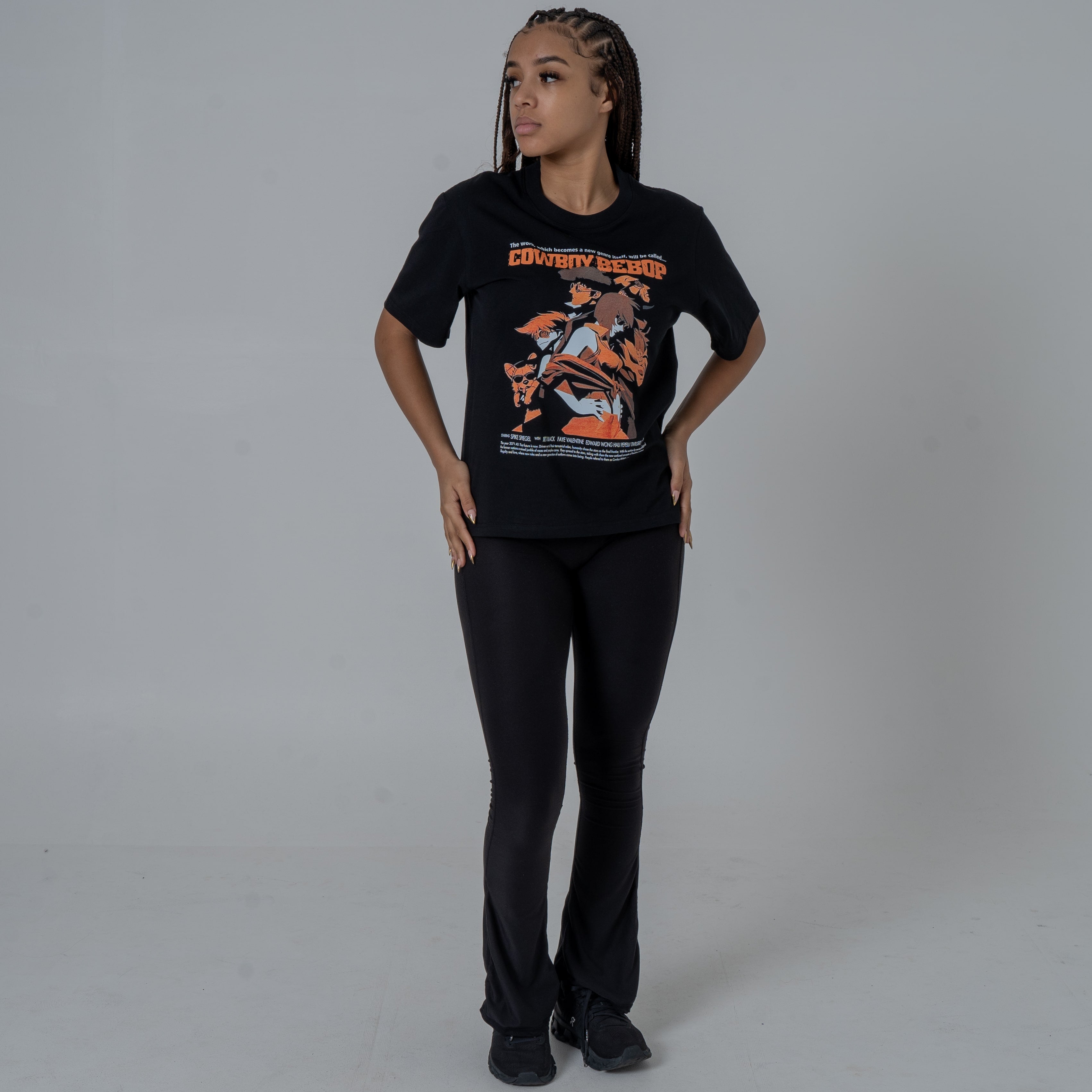 Full body shot of a Female model in a studio wearing a black anime T-shirt featuring an orange, vintage-hued Cowboy Bebop graphic print.