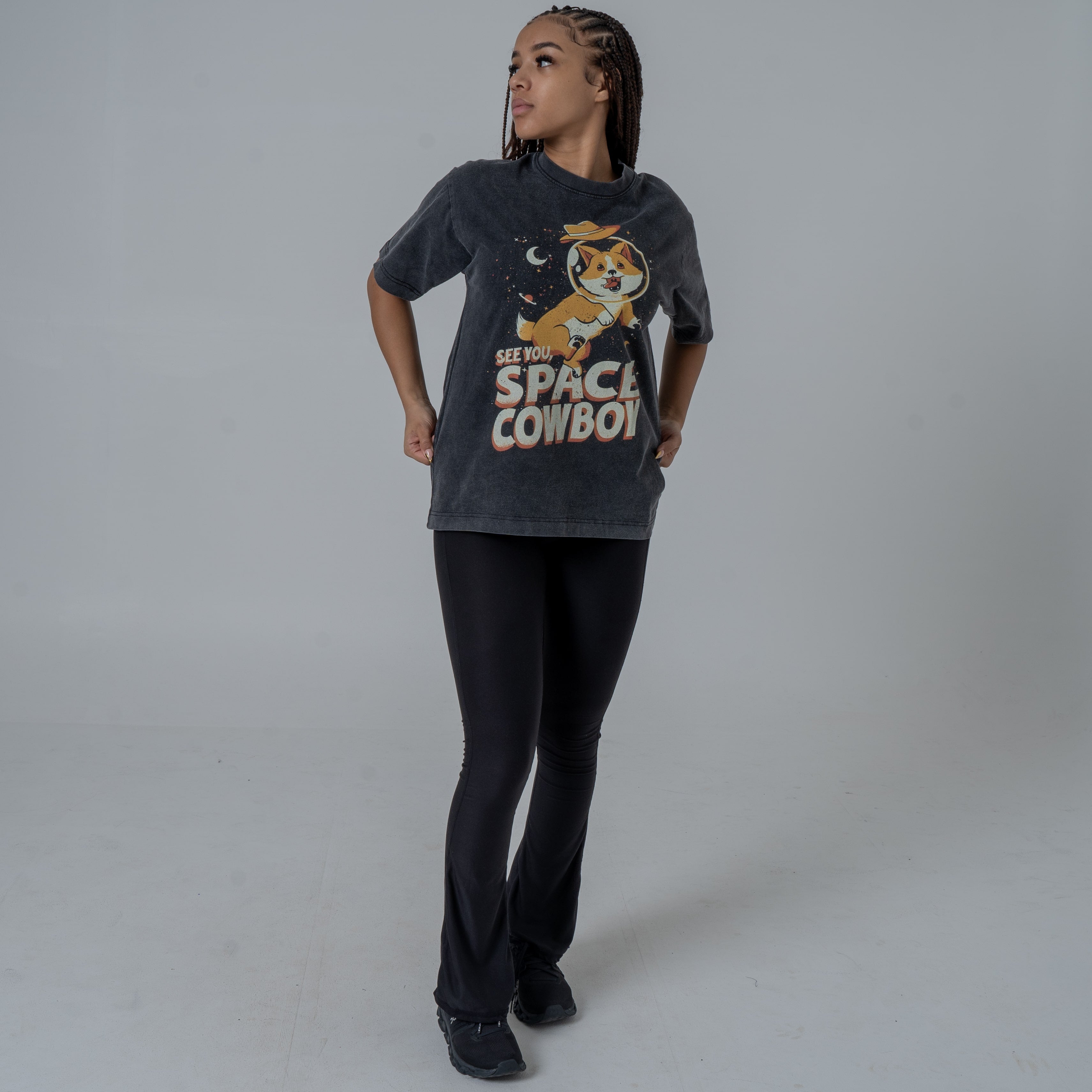 Female Model wearing a vintage-style black T-shirt featuring Ein, the dog from Cowboy Bebop, in a space helmet with the text 'See You Space Cowboy,' styled with black flared pants and black sneakers.