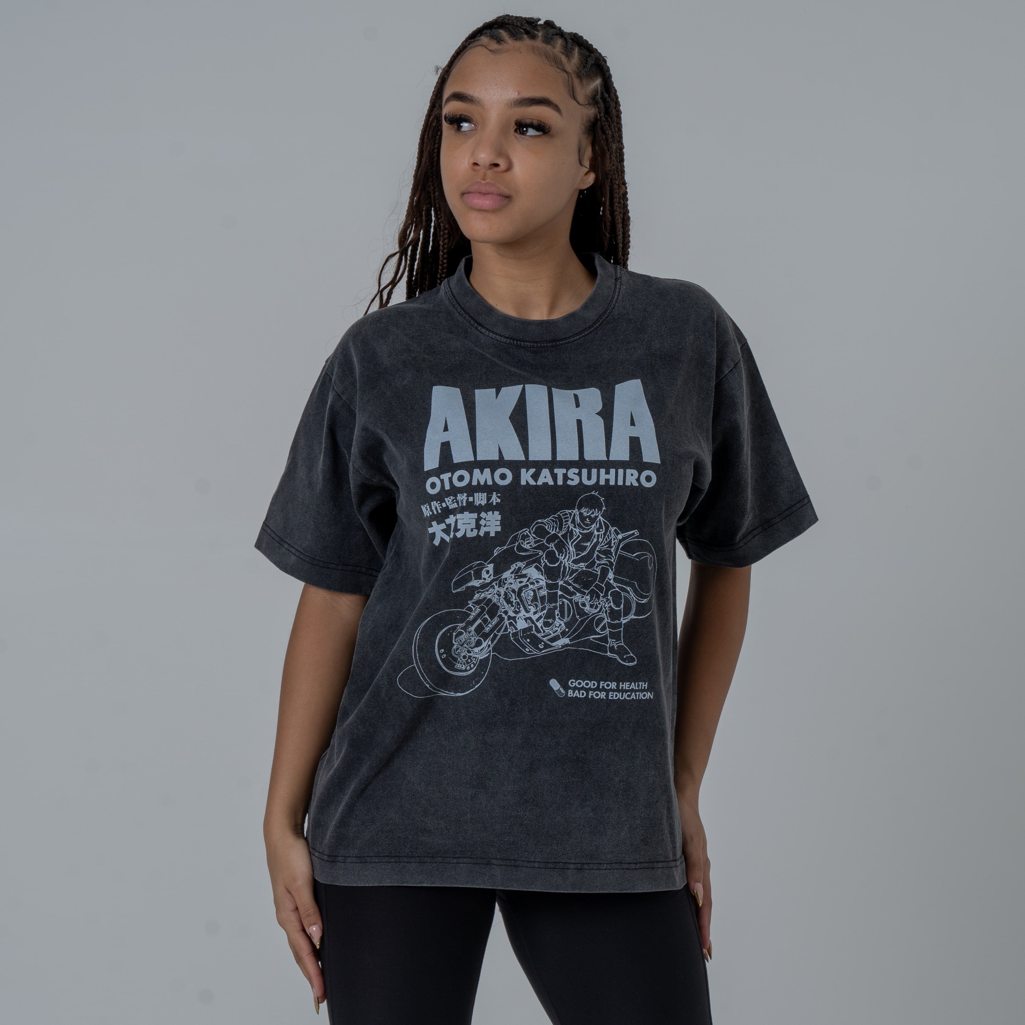 Half body shot of a female model in a studio wearing a black vintage-washed anime T-shirt featuring a white Akira graphic with Kaneda riding his iconic motorcycle.